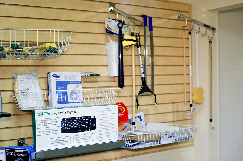 This picture shows a wall display of different self-care assistive devices along with a large print keyboard